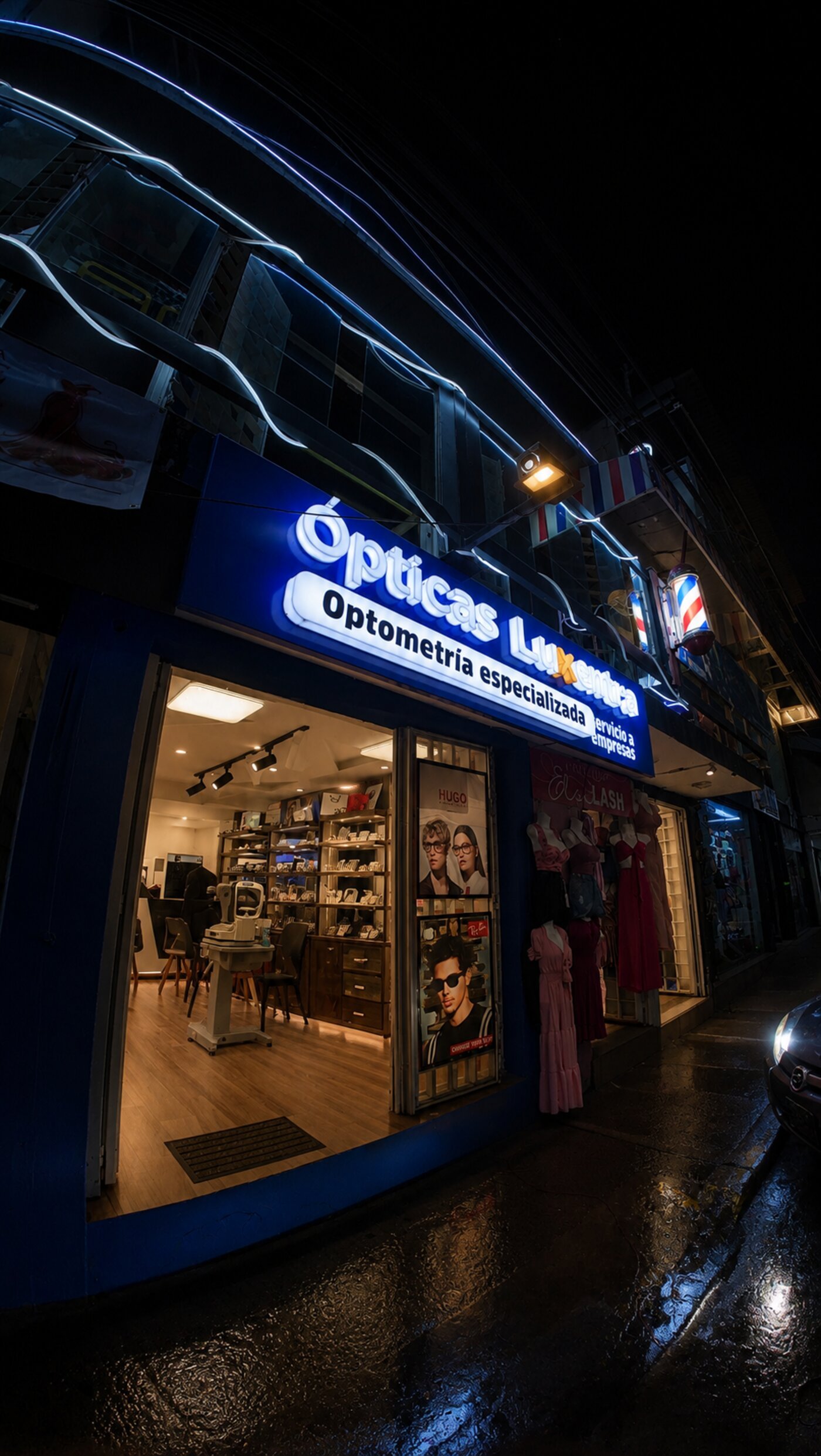 Fachada de Ópticas Luxentra iluminada de noche